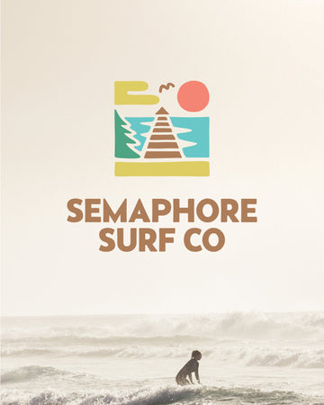Semaphore Surf Co. logo with a jetty and sun graphic above a photo of a surfer in rough surf