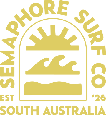 A circular gold graphic with the words 'SEMAPHORE SURF CO' around an arch, featuring a stylized sun, wave, and surfboard silhouette, with 'EST 1926 SOUTH AUSTRALIA' at the bottom on a black background.