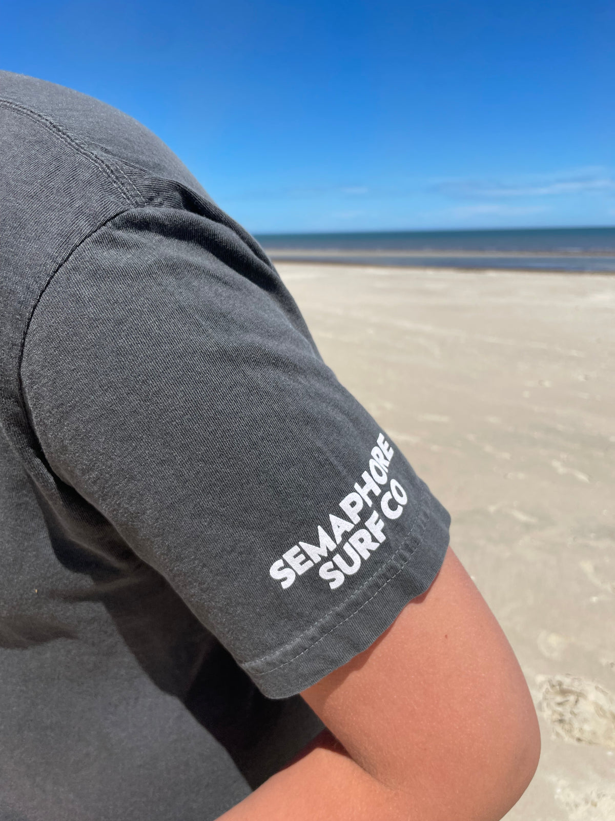 Close-up of the Semaphore Surf Co. wordmark on the sleeve of the pepper tee