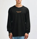 Model wearing the black Semaphore Surf Co. emblem long sleeve tee, front view with the wordmark on the chest